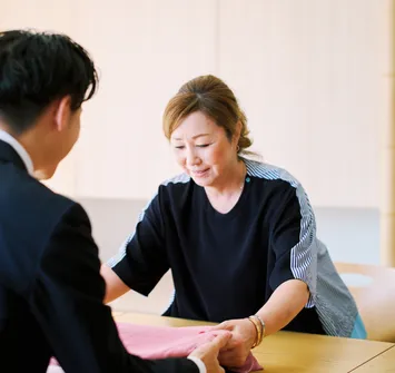 買取訪問のために自宅へ来たバイセルの社員に着物を手渡している女性の写真