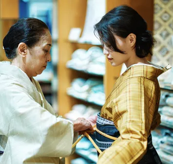 バイセルの販売店舗にて店舗スタッフと一緒にリユース着物を着付け・試着する女性の写真